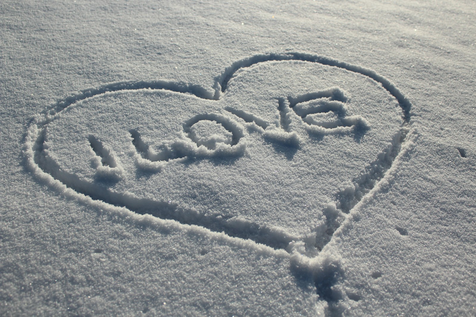 A heart drawn in the snow on a sunny day